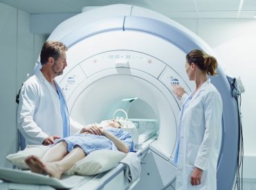 Male and female doctors preparing patient for MRI scan in hospital